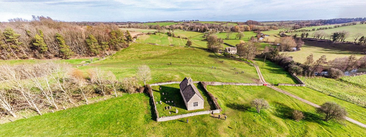 Bird's eye view of a rural church in amongst rolling fields
