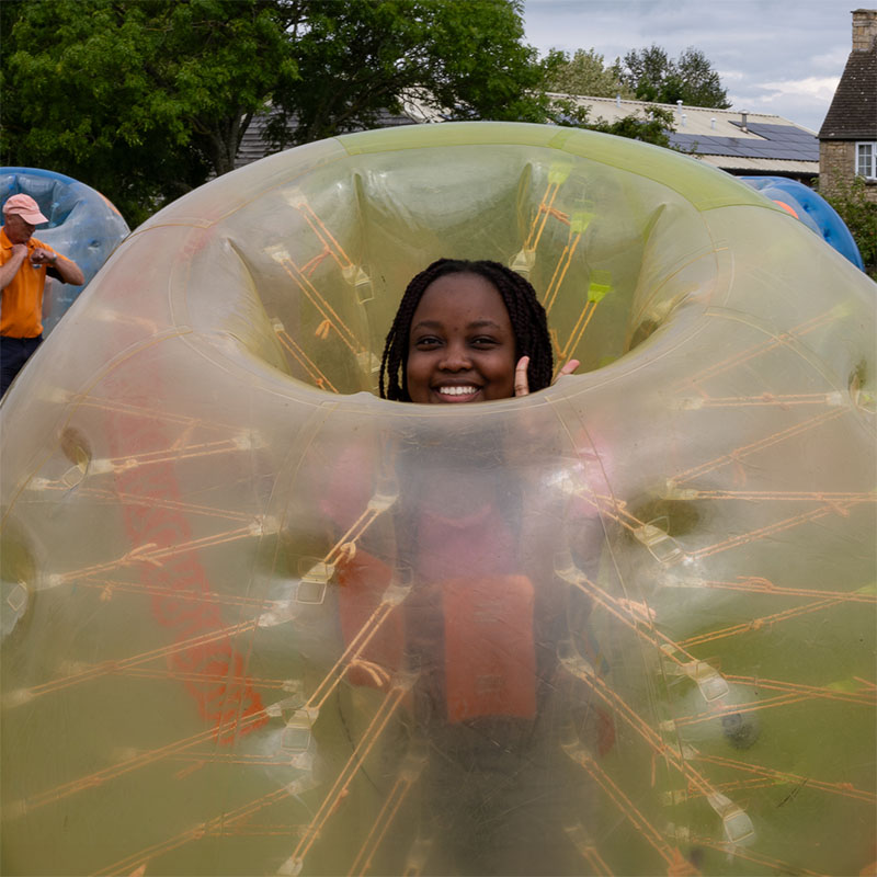 A teenage girl smiles from inside a zorb ball