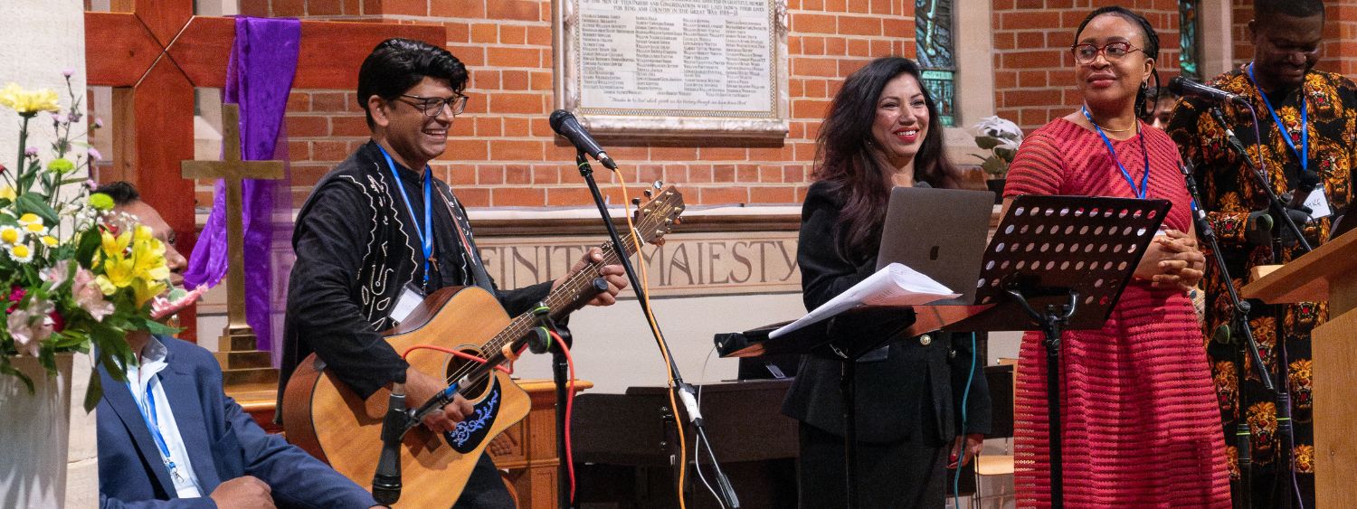 A worship band smile at the front of a church