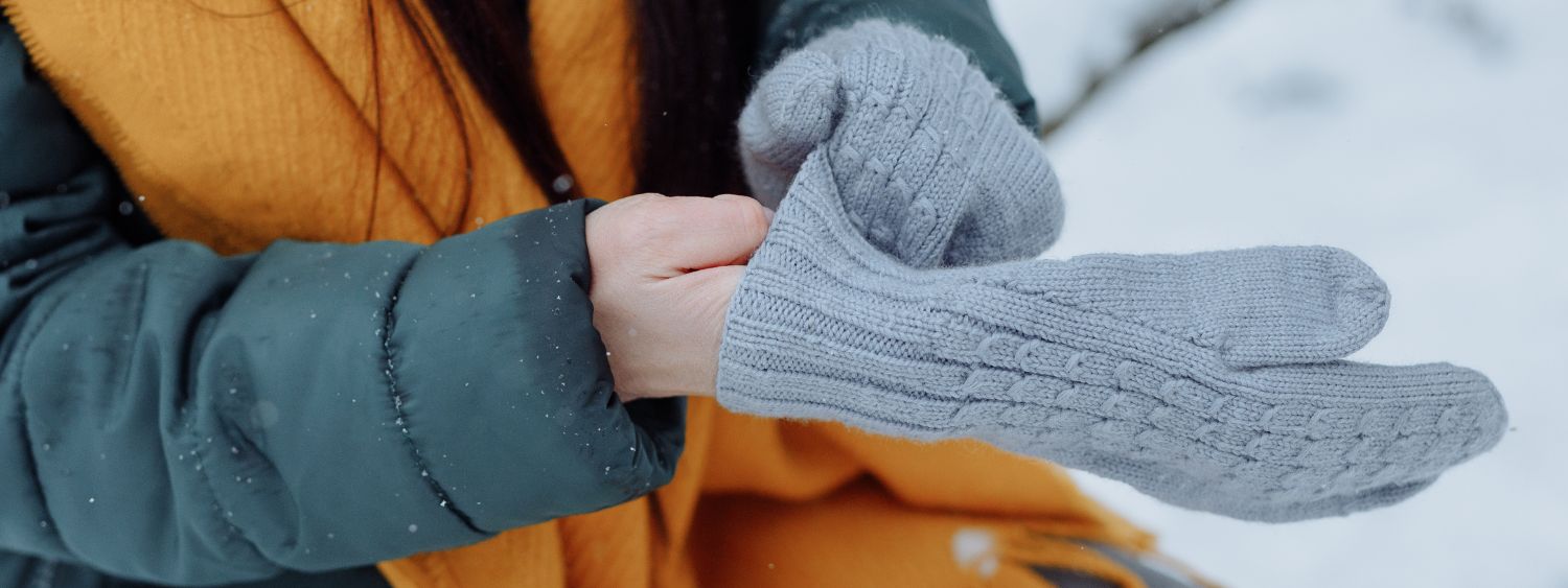 A person pulls on warm gloves in the snow