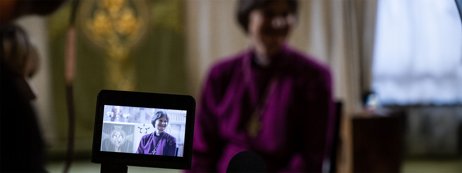 A bishop smiles through a camera viewfinder
