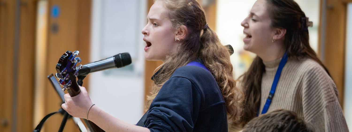 A teenage girl plays guitar, leading worship