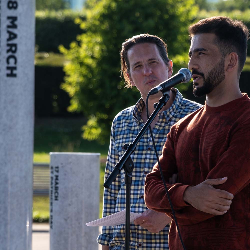 A man from Afghanistan speaks into a microphone outside in the Milton Keynes Rose 