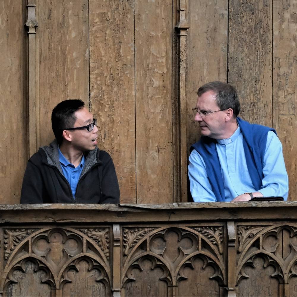 Revd Will Donaldson and a congregation member sit in the choir stalls at St Mary the Virgin Church