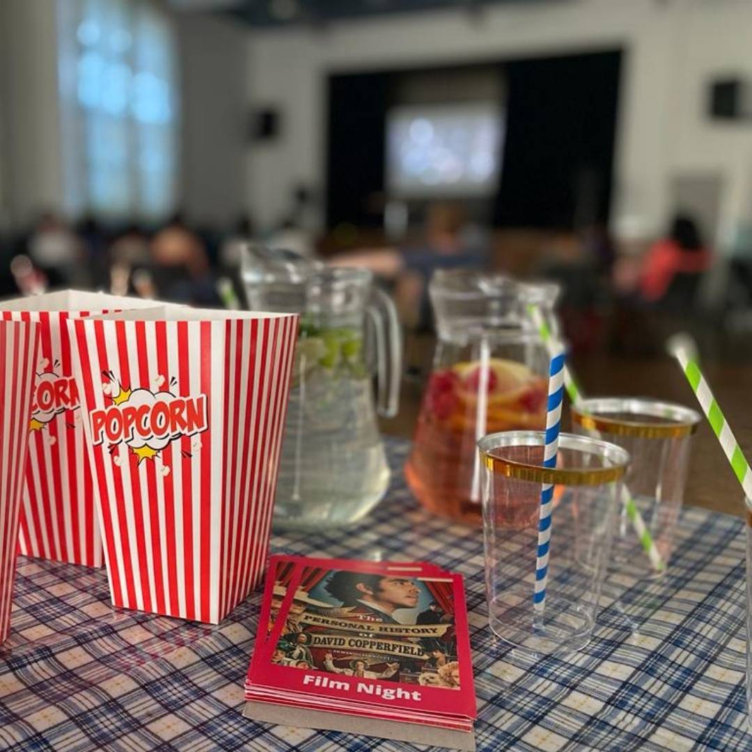 Red and white striped popcorn boxes and drinks glasses sitting on a table in front of a large screen in St Clements Church