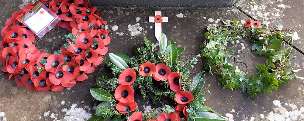 Remembrance wreaths laid at a memorial. From the oldest on the left to the newest on the right, they gradually are made of less and less plastic and more natural materials.