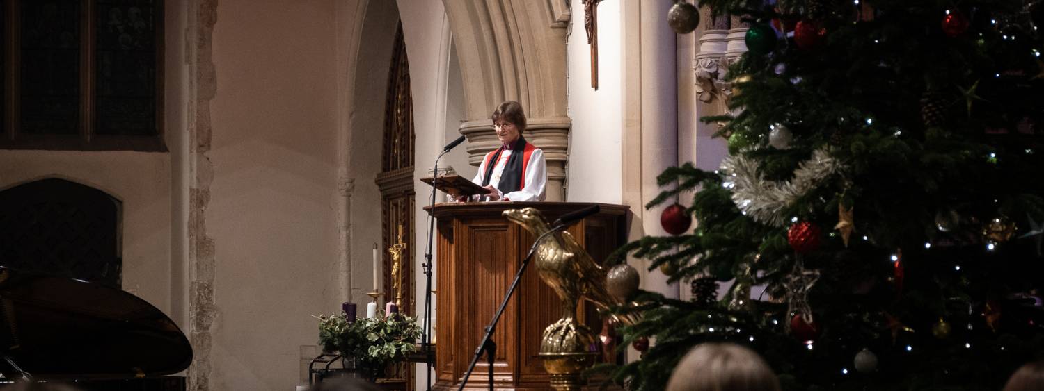 Bishop OIivia speaking from pulpit at Reading Minster among Christmas Tree and Christmas decorations