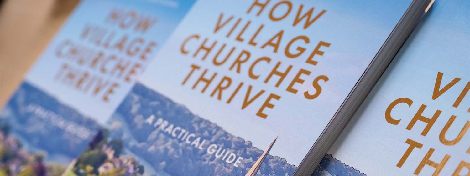 Stack of How Village Churches Thrive guidebooks