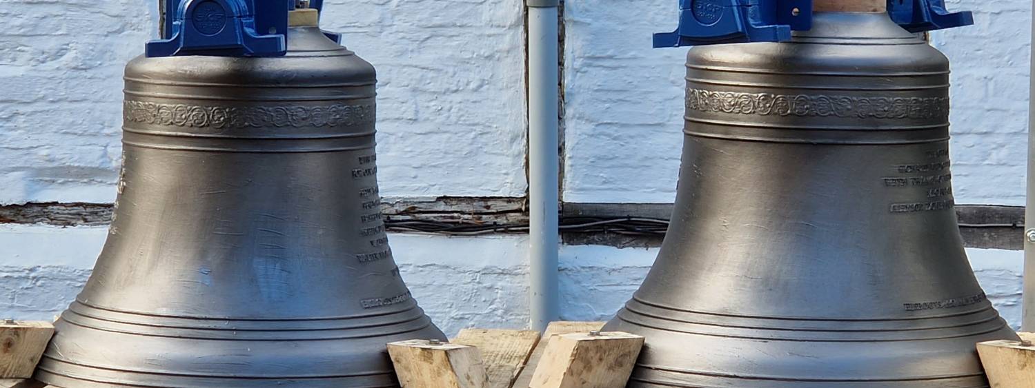 Two large silver church bells sit side by side